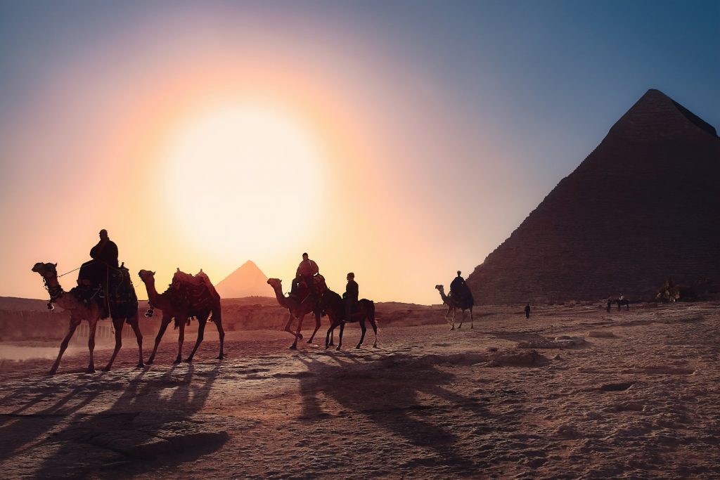 Kamelenkaravaan in Egypte met een pyramide op de achtergrond