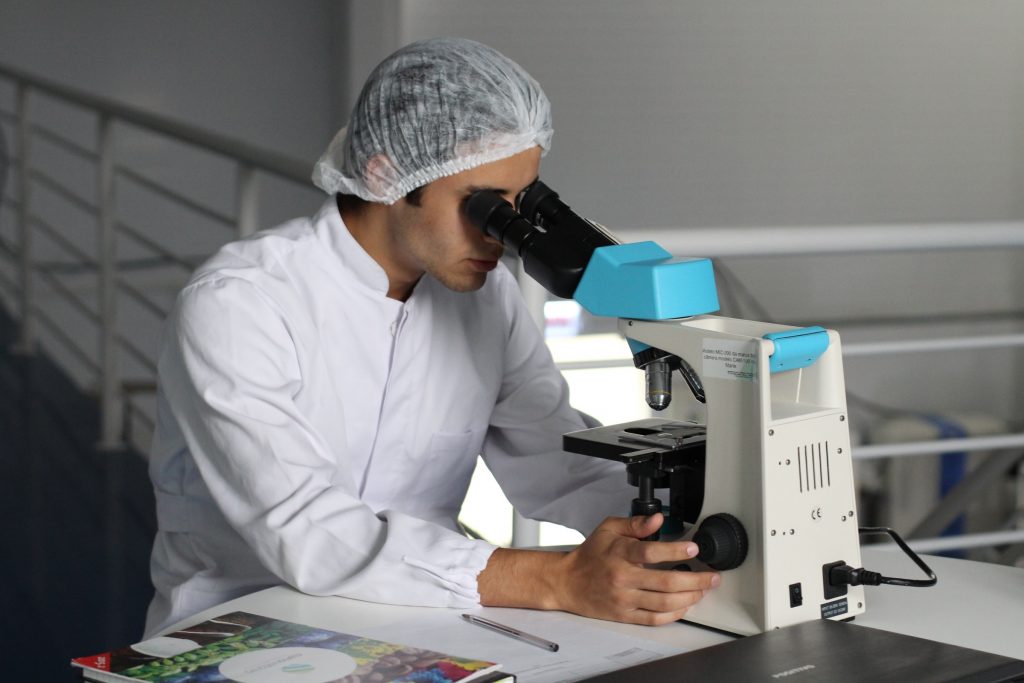 Laborant werkend achter een microscoop